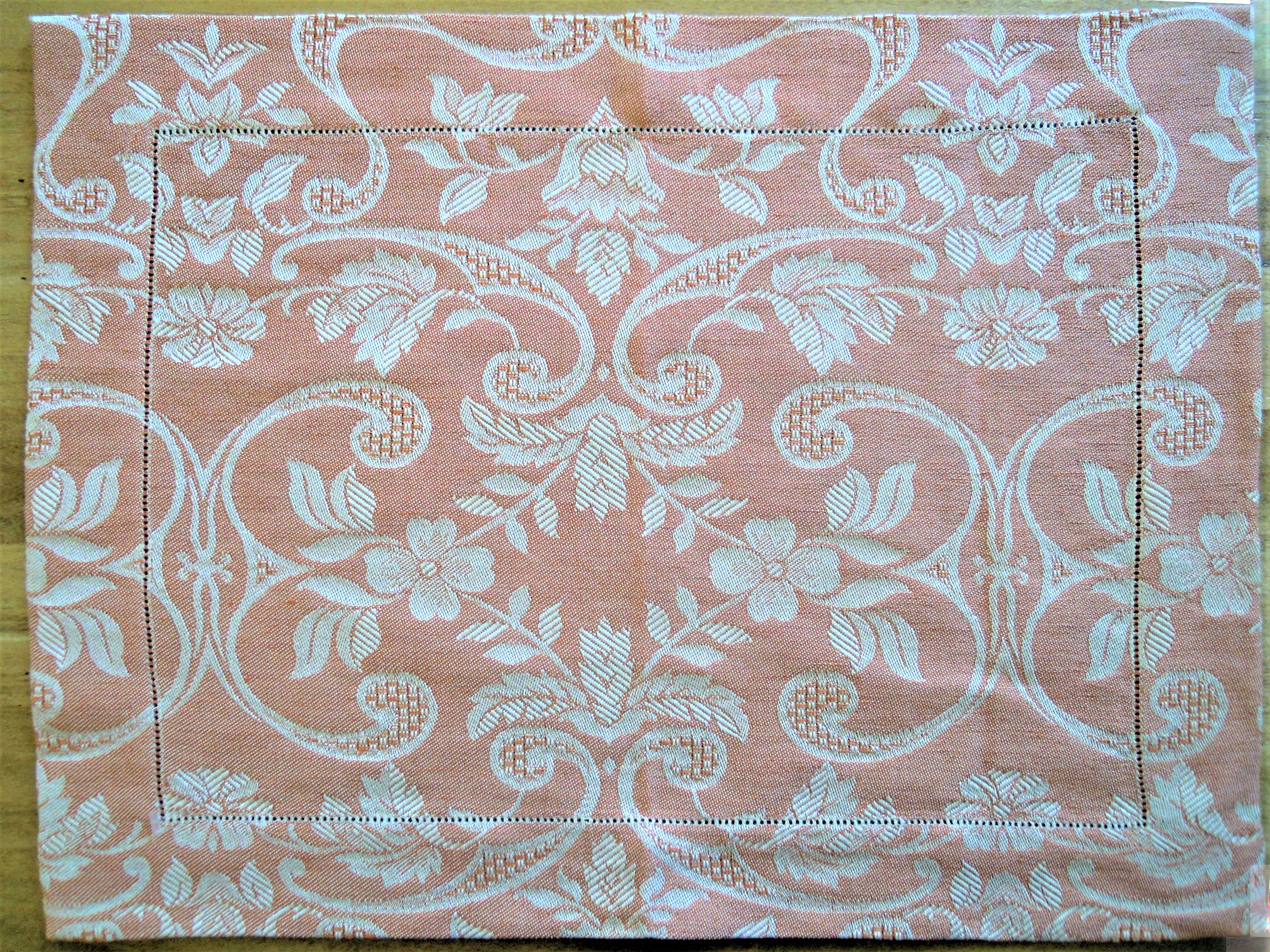 Tovaglietta per colazione, tessitura artigianaTovaglietta per colazione, tessitura artigianale in misto lino/cotone, con disegno floreale e finitura punto a giorno, colore rosso, cm 45x60.le